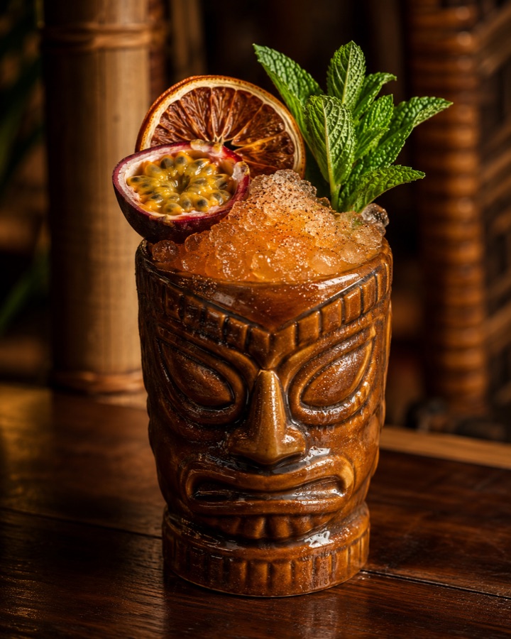 Lao Tiki Punch in a carved tiki mug with passion fruit and mint
